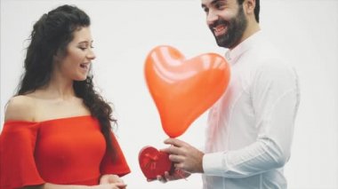 Güzel genç çift evde. Öpücük ve birlikte iyi eğlenceler. Sevgililer günü kutlaması. El ve bir kalp şeklinde balon hediye kutusunda.