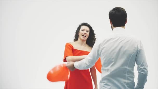 Vackra romantiska par isolerade på vit bakgrund. En attraktiv ung kvinna och stilig knock varandra med ballonger i form av hjärtat i sina händer. Leende. Happy Valentine — Stockvideo