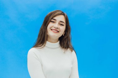 Bir gülümseme ile mavi bir arka plan bir kız. Mavi bir arka plan üzerinde bir kız.