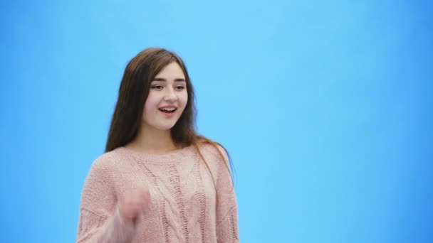 Beautiful young woman with clean, perfect skin. Looking straight the girl raises her hand up during this waving greeting. — Stock Video