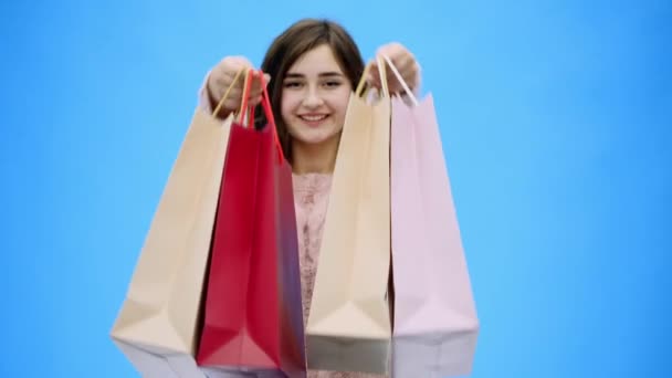 Jonge mooie meisje doet ongelooflijk aangenaam winkelen. Gedurende deze tijd legt ze boodschappentassen op haar armen. — Stockvideo