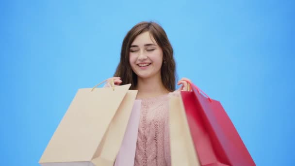 Genç güzel kız inanılmaz alışveriş hoş yapıyor. Bu sırada o elleri ve alışveriş torbaları yukarı yükseltir. Aynı zamanda son derece sevindirici. — Stok video