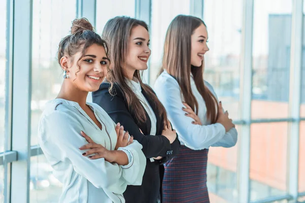 With pleasure, three business women cross their arms, looking at the camera.