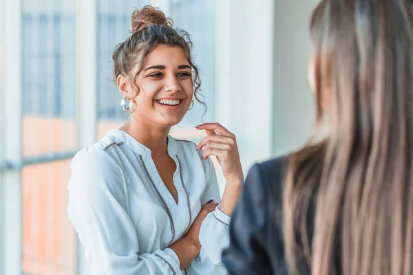 Três lindas jovens empresárias. Fala com colegas com uma cópia do espaço no fundo de seus colegas — Fotografia de Stock