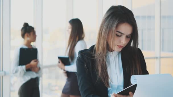 Hermosa mujer de negocios morena en traje blanco con carpeta de documentos en sus manos al aire libre — Vídeos de Stock