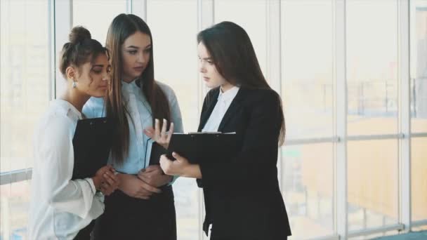 Група дружніх трьох багатоетнічних бізнесменів стоять в офісному залі, проводять папери, вивчають фінансову звітність . — стокове відео