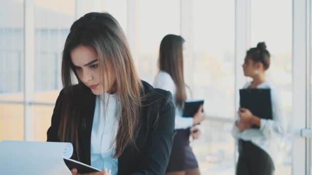 Hermosa mujer de negocios morena en traje blanco con carpeta de documentos en sus manos al aire libre . — Vídeos de Stock