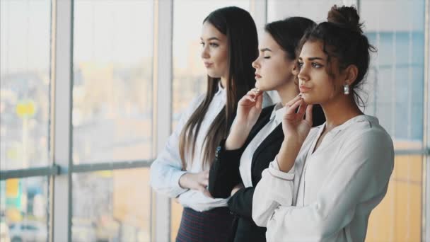 Drei junge schöne brünette Geschäftsfrauen im Büro. alle seriösen, gefalteten Hände schauen zur Seite — Stockvideo