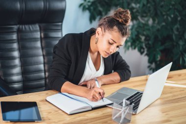 İş elbiseleri giymiş genç iş kadını ofiste olduğunu.