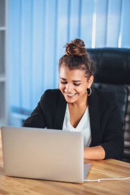 İş elbiseleri giymiş genç bir kız bir dizüstü bilgisayarda çalışıyor.