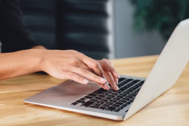 İş elbiseleri giymiş genç bir kız bir dizüstü bilgisayarda çalışıyor.