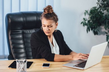 İş elbiseleri giymiş genç bir kız bir dizüstü bilgisayarda çalışıyor.