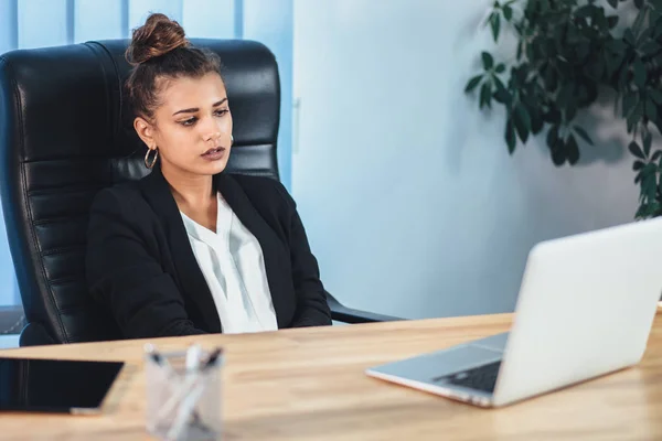 A young girl dressed in business clothes is working on a laptop. — Stock Photo, Image