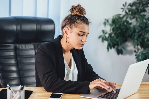 A young girl dressed in business clothes is working on a laptop. — Stock Photo, Image