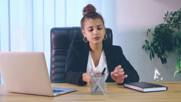 La ragazza è vestita con abiti eleganti mentre è seduta in ufficio a digitare su un computer portatile . — Video Stock