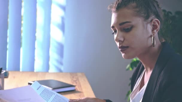 A menina está vestida com roupas elegantes, sentada no escritório . — Vídeo de Stock