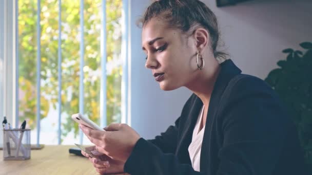 Het meisje is gekleed in stijlvolle kleding, zittend in het kantoor. — Stockvideo