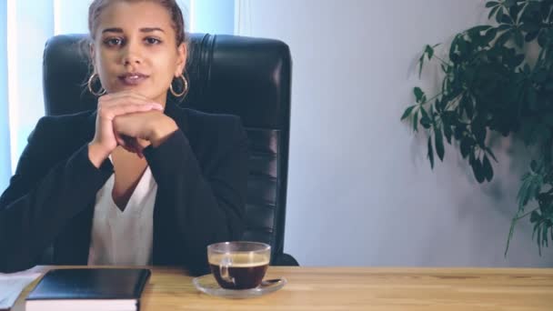 La fille est vêtue de vêtements élégants, assise dans le bureau. Pendant ce temps, elle sourit vraiment . — Video