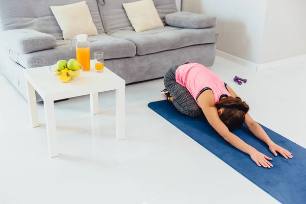 Young girl doing stretching exercise. Nice graceful girls with long hair in pantyhose occupied by yoga on a lilac carpet. — Stock Photo, Image