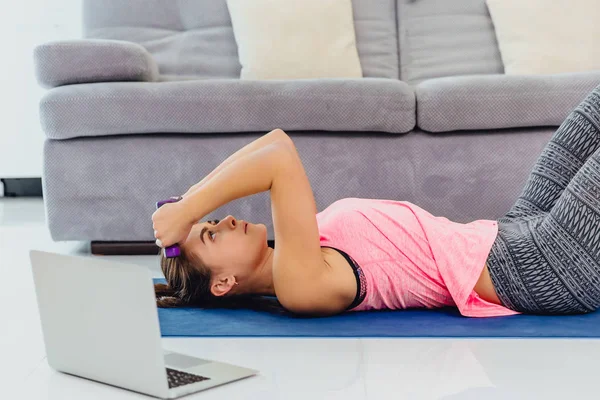 Young girl looking at laptop and doing exercises at home. — Stock Photo, Image