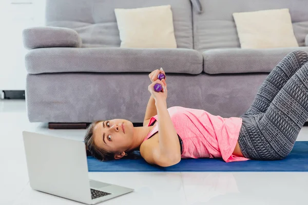 Young girl looking at laptop and doing exercises at home. — Stock Photo, Image