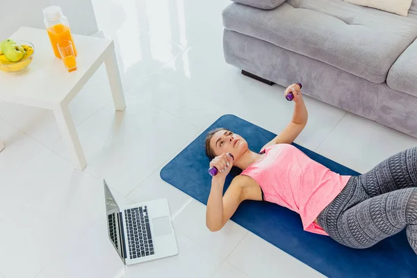 Young girl looking at laptop and doing exercises at home. — Stock Photo, Image