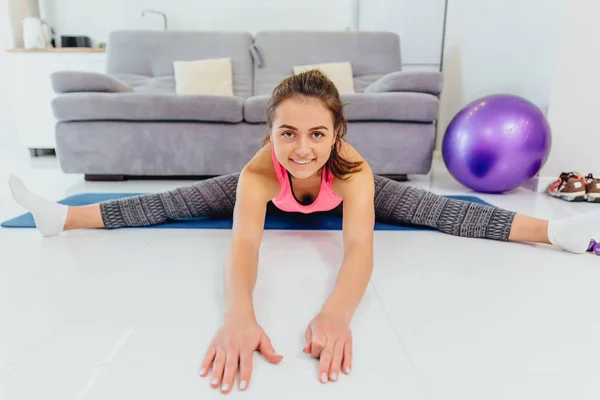 A great young girl makes different kinds of exercises stretch marks approaches — Stock Photo, Image