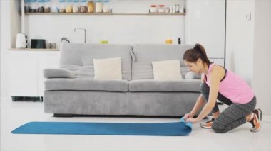 Evde oturma odasında çalıştıktan sonra mavi koşu veya bir fitness mat güzel kadın giyinmiş bir genç yakın çekim.
