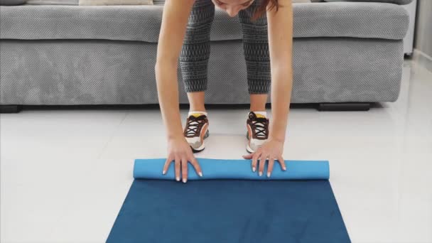 Primer plano del complejo femenino de yoga azul o colchoneta de fitness después del trabajo en casa en la sala de estar . — Vídeos de Stock