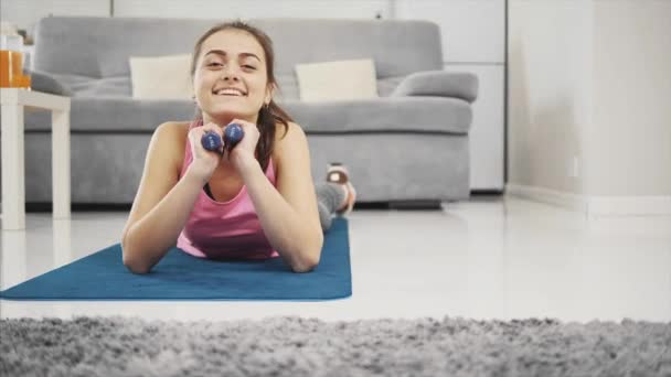 Una chica disfruta de fitness en casa mientras sonríe . — Vídeos de Stock