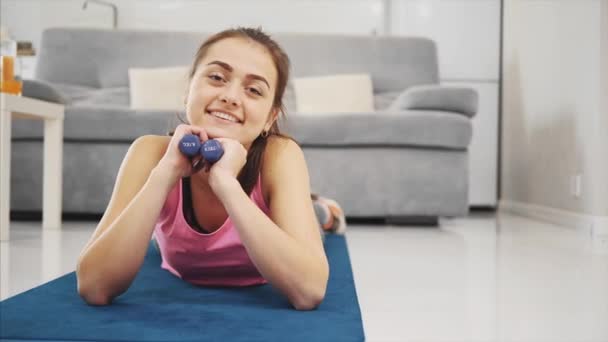 Uma menina gosta de fitness em casa enquanto sorri . — Vídeo de Stock