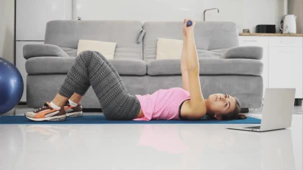 La fille fait des devoirs tout en faisant des exercices à partir de l'ordinateur portable . — Video