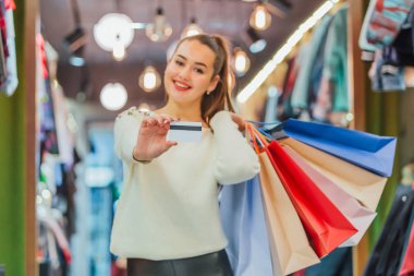 Kızı tutan bir kredi kartı ve bir ile alışveriş torbaları.