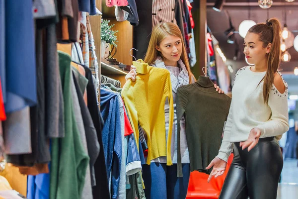 Two friends choose sweaters during shopping. Feel good, smiling and laughing. — Stock Photo, Image
