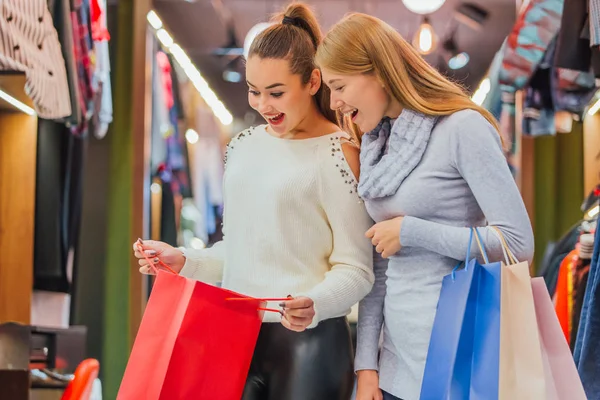 Chicas jóvenes comprando un montón de cosas en la tienda guardan bolsas de compras . — Foto de Stock