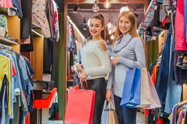Chicas jóvenes comprando un montón de cosas en la tienda guardan bolsas de compras . — Foto de Stock