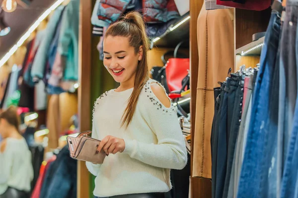 En la tienda, la joven abre su billetera y quiere encontrar una tarjeta bancaria . — Foto de Stock