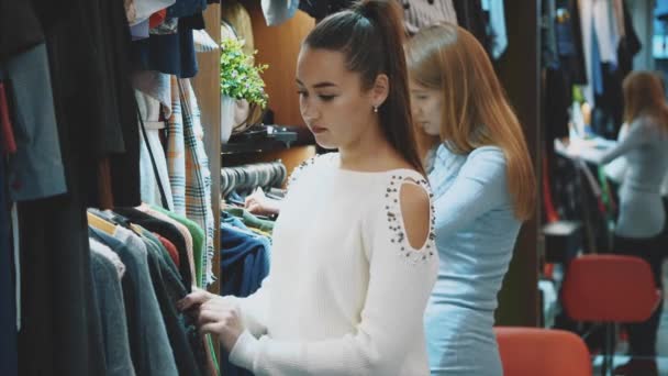 Una hermosa dama en una tienda de ropa elige un armario adecuado para ella . — Vídeos de Stock
