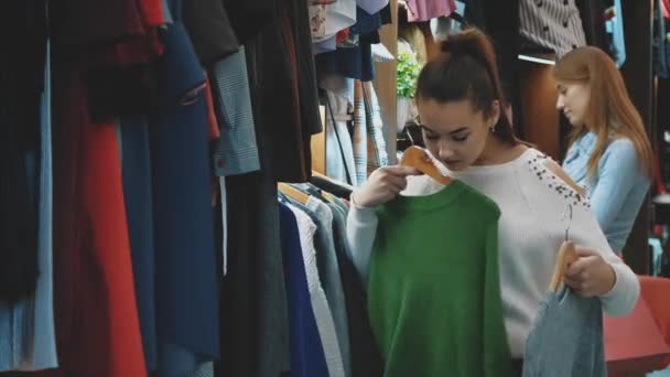 Uma bela senhora em uma loja de roupas escolhe um guarda-roupa adequado para si mesma . — Vídeo de Stock