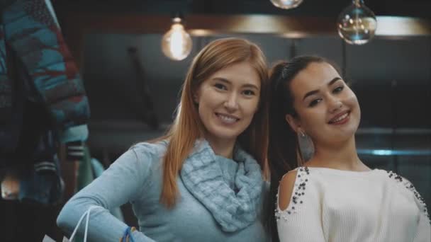 Dos hermosas mujeres jóvenes, disfrutando de las compras en la tienda, están muy emocionados de recibir un gran placer de ir de compras . — Vídeo de stock