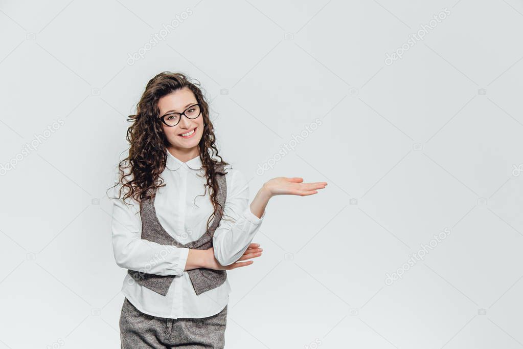 Beautiful young woman standing lifts her right arm. Looking how something holds in a white background