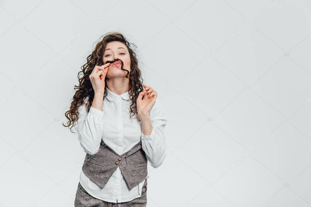 Young business lady with beautiful curly hair on a white background. During this time he puts his hair like a mustache