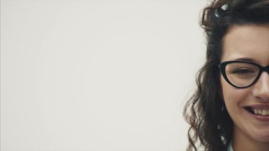 Muhteşem saçlı Genç güzel kız. Beyaz bir arka plan üzerinde. Gözlükte içtenlikle gülümsüyor giyinmiş.