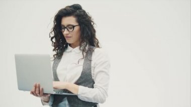 Gözlüklü genç enerjik kız beyaz bir arka plan üzerinde duruyor.