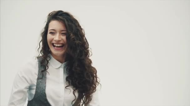 Mujer de negocios sonriente vestida con camisa blanca. De pie sobre un fondo blanco sonríe genuinamente bailando . — Vídeo de stock