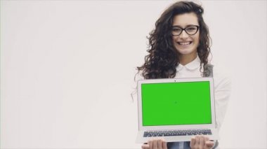 Kıvırcık saçlı genç enerjik sevimli kız bir dizüstü bilgisayar onun elinde tutar. Yeşil bir ekran ile bir dizüstü bilgisayar