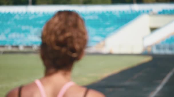 Retrato de uma garota forte em sportswear correndo no estádio. Menina bonita corre no estádio e ouve o jogador . — Vídeo de Stock