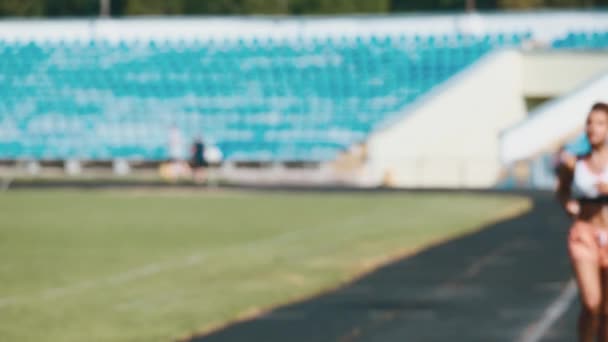 Portret silna dziewczynka w sportowej uruchomiona na stadionie. Piękna dziewczyna biegnie na stadionie i słucha gracz. — Wideo stockowe