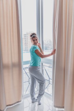 Genç modeller ile tam boy pencereler, modern bir yüksek katlı evde çıplak ayakla dans sabah, yeni gün, yeni bir daire aldım karşılama kollarını uzanıyordu. Mutlu, canlı, rüyada duygusu.