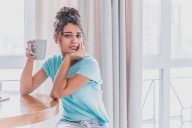 Eller sıcak aroma çay ile yumuşak rahat fotoğraf genç kızın sıcak örme kazak. Dev örme şal üzerinde oturan kız.